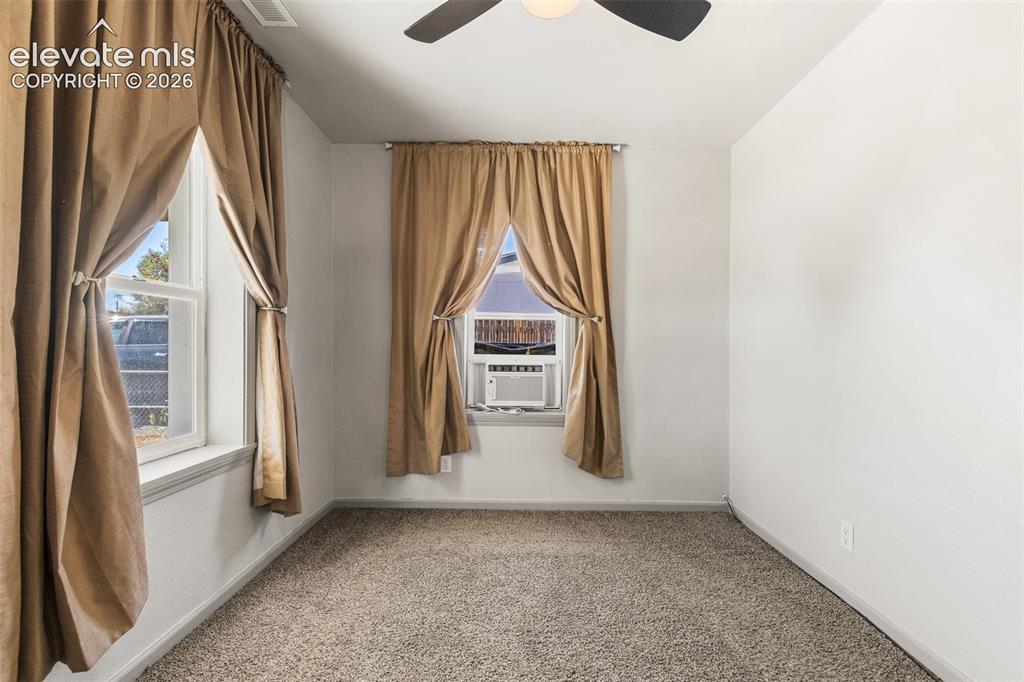 Image 7 of 23: Carpeted room featuring multiple windows, a ceiling fan, and a wall-mounted
