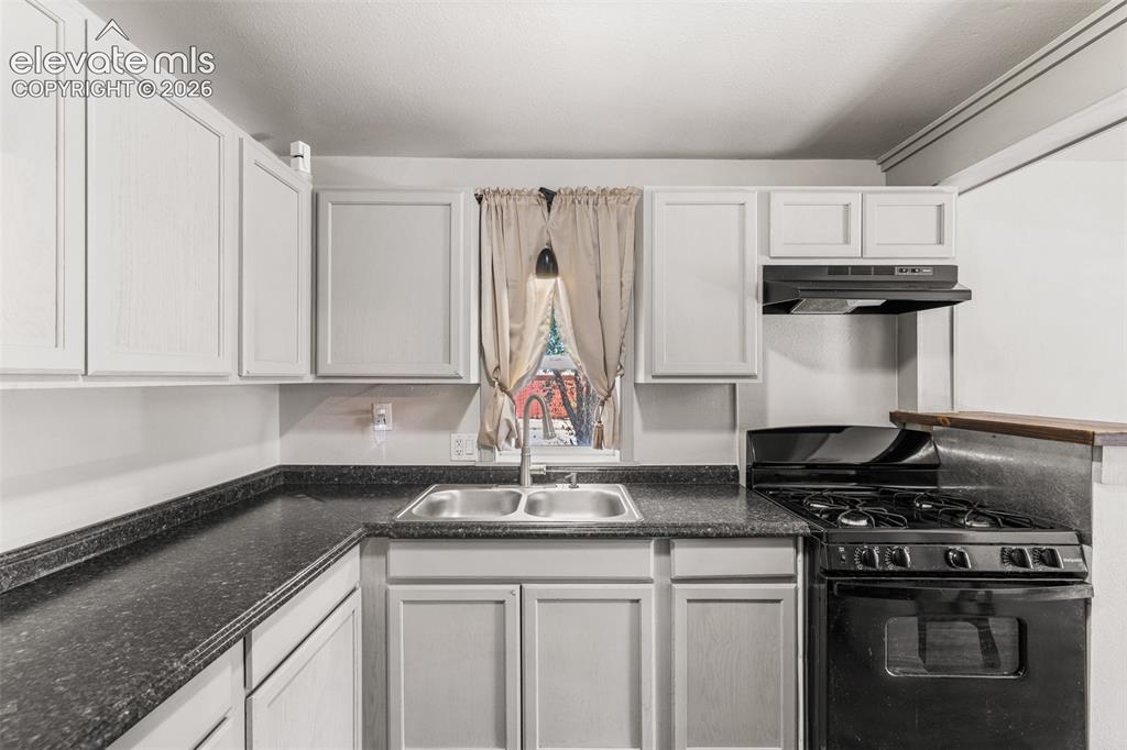 Image 9 of 23: White shaker-style cabinetry, dark speckled countertops, stainless steel do