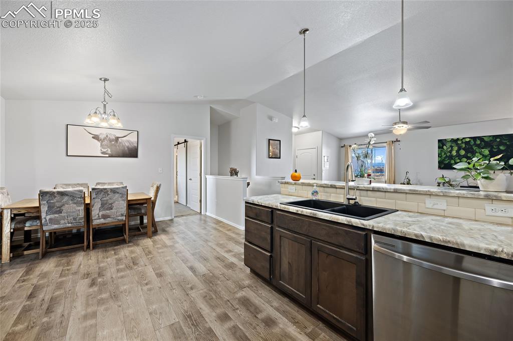 Image 15 of 36: Kitchen with stainless steel dishwasher, dark brown cabinetry, lofted ceili
