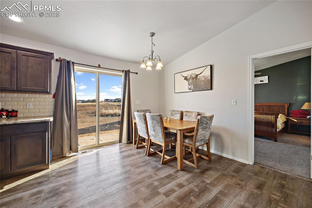 Image 18 of 36: Dining area featuring lofted ceiling, a chandelier, and light wood-style fl