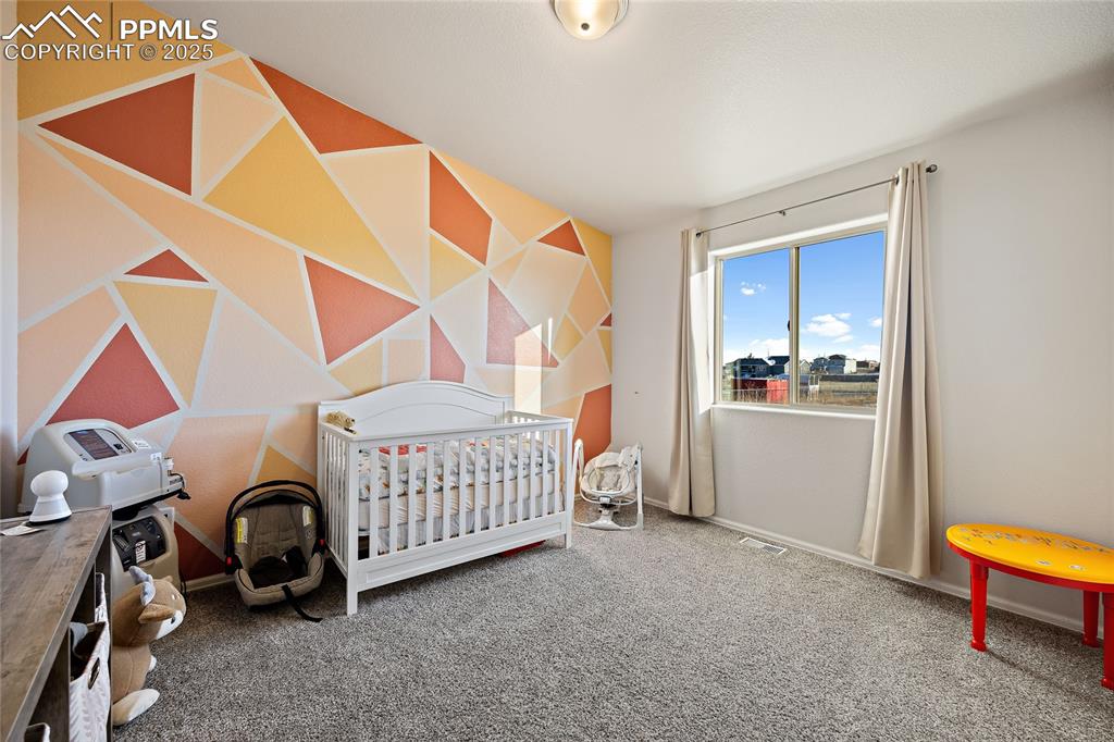 Image 23 of 36: Bedroom featuring a nursery area and carpet flooring
