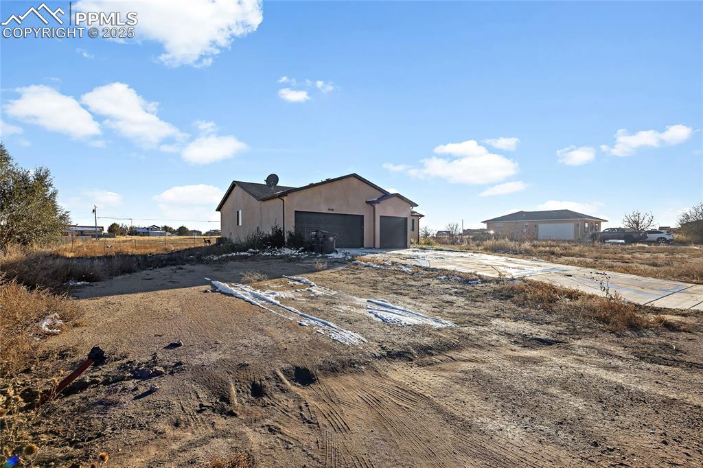 Image 3 of 36: View of side of property featuring a garage and stucco siding