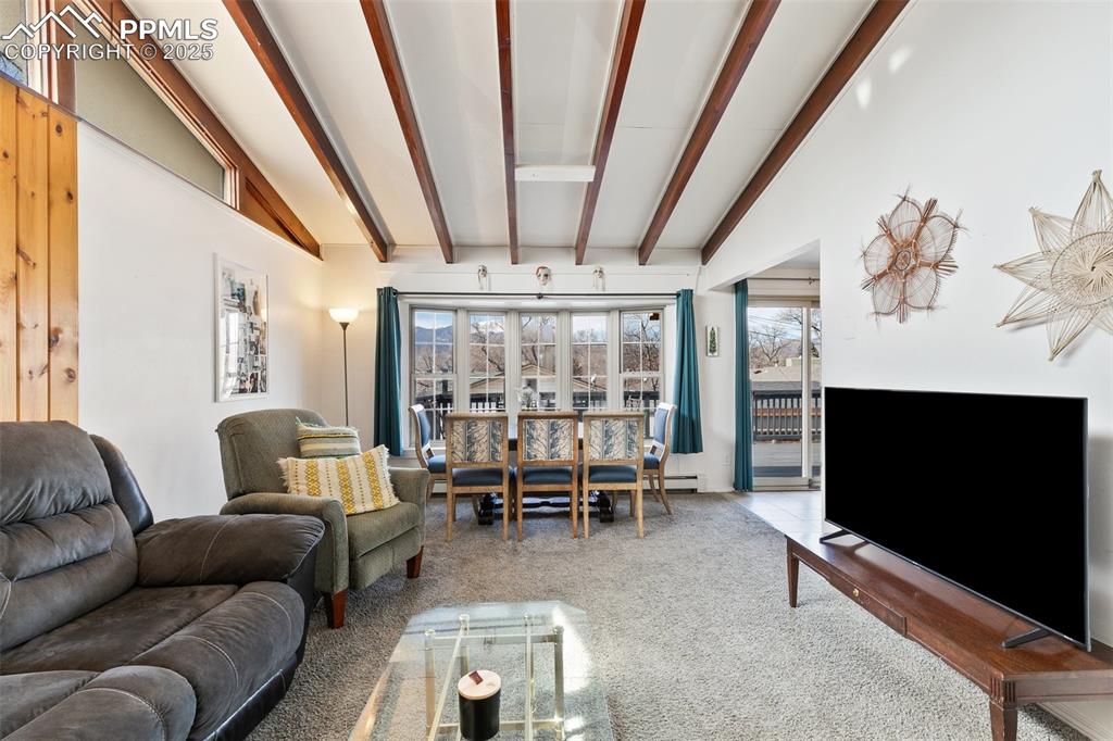 Image 25 of 49: Carpeted living area featuring vaulted ceiling with beams