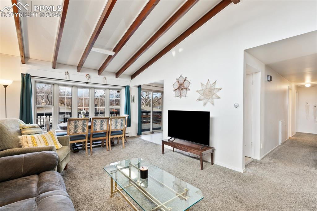 Image 26 of 49: Living room featuring beamed ceiling, plenty of natural light, and carpet