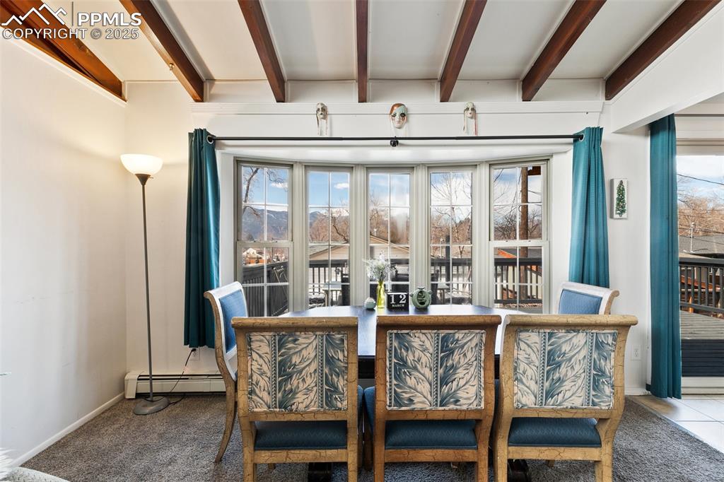 Image 27 of 49: Dining area with beamed ceiling, carpet flooring, a healthy amount of sunli