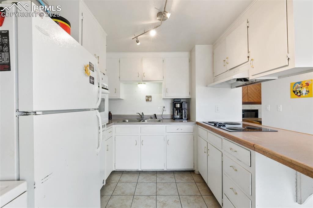 Image 29 of 49: Kitchen featuring light countertops, light tile patterned floors, white app