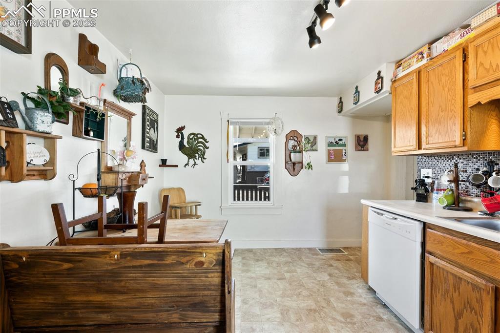 Image 42 of 49: Kitchen with visible vents, tasteful backsplash, brown cabinetry, light cou