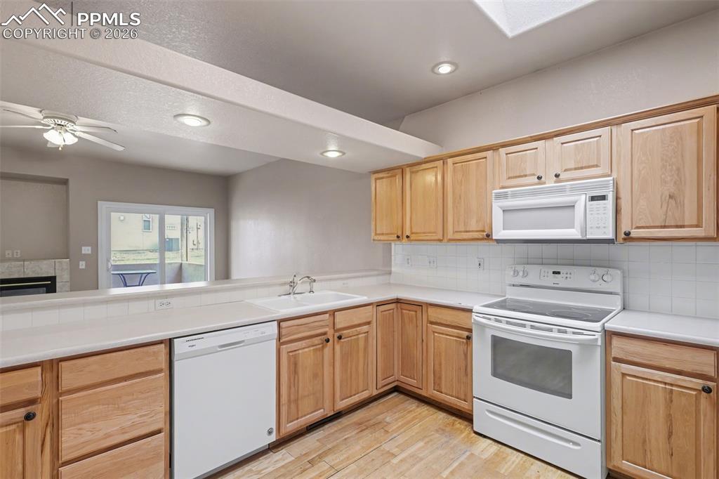 Image 12 of 28: Kitchen featuring white appliances, light wood finished floors, a skylight,