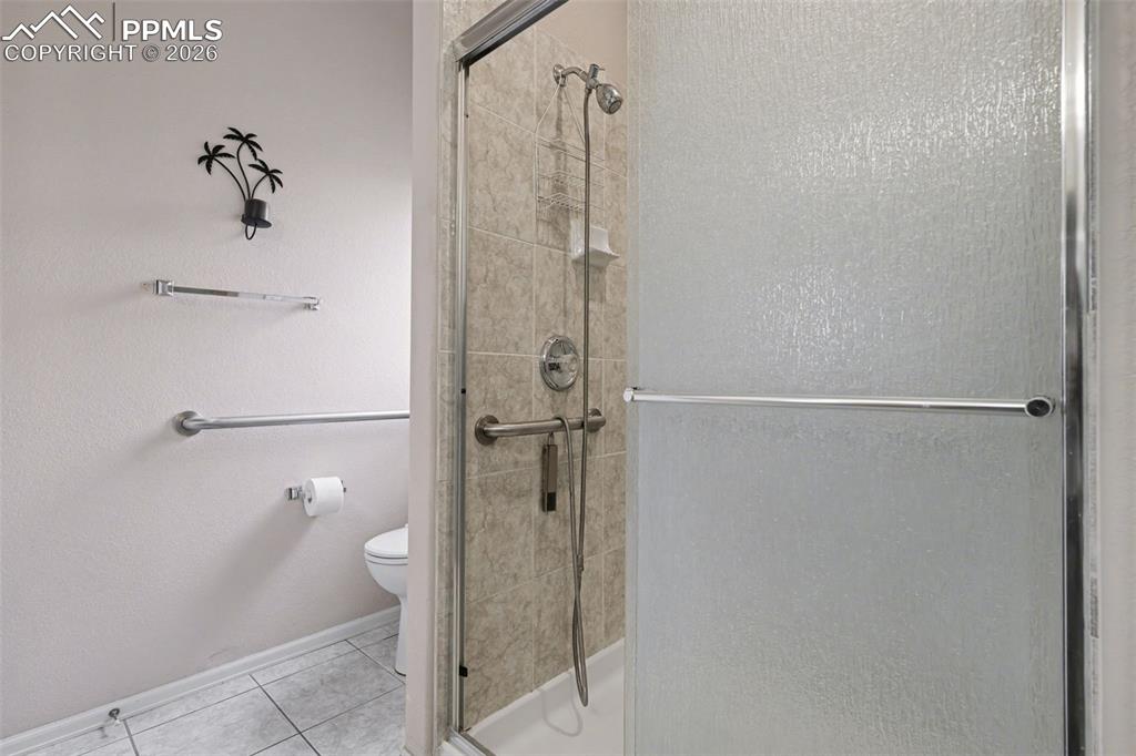 Image 21 of 28: Bathroom with double vanity, a stall shower, and light tile patterned floor
