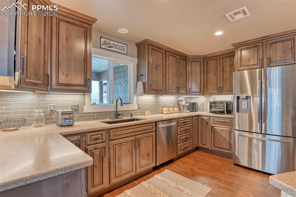 Image 12 of 50: Kitchen with stainless steel appliances, light stone countertops, light woo