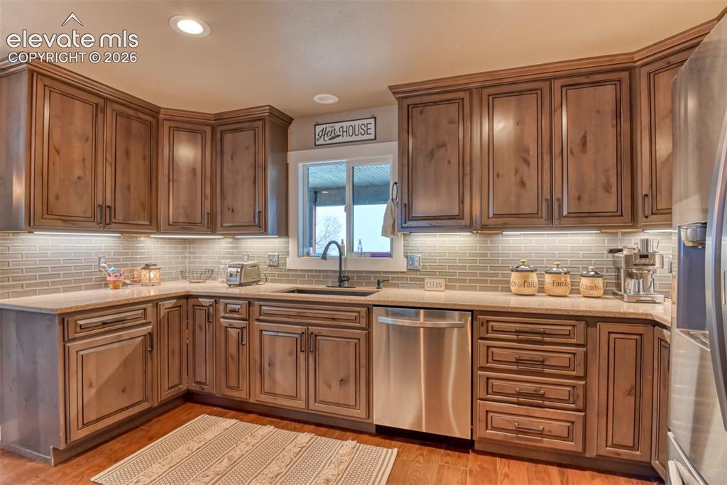 Image 12 of 50: Kitchen with stainless steel appliances, light stone countertops, tasteful