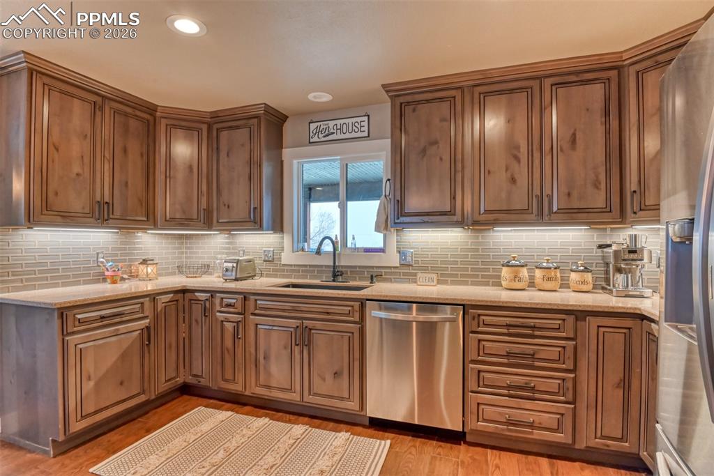Image 13 of 50: Kitchen with stainless steel appliances, light stone countertops, tasteful
