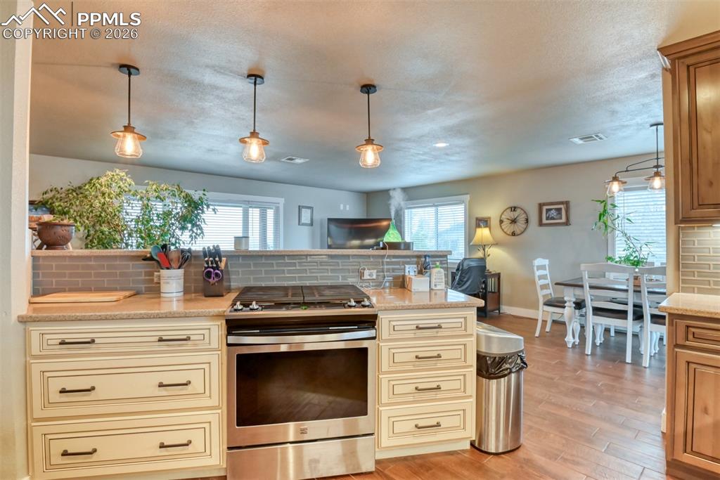 Image 14 of 50: Kitchen featuring cream cabinetry, decorative backsplash, stainless steel g