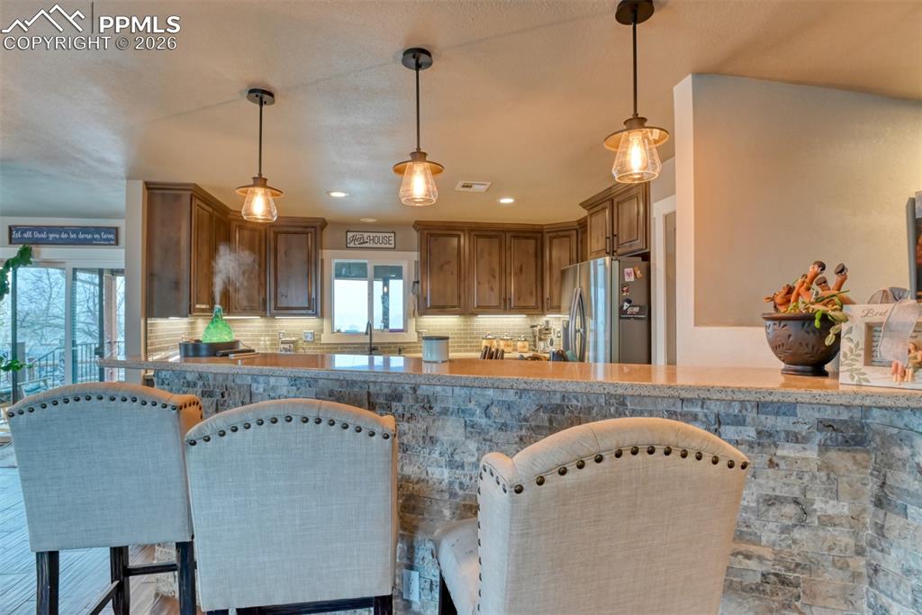 Image 15 of 50: Kitchen featuring stainless steel fridge, tasteful backsplash, a breakfast