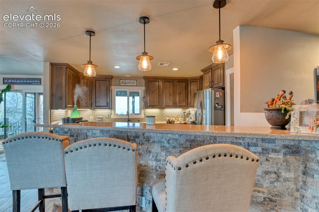 Image 16 of 50: Kitchen featuring stainless steel fridge, tasteful backsplash, a breakfast
