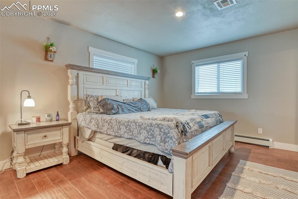 Image 24 of 50: Bedroom with a baseboard heating unit and light wood-style floors