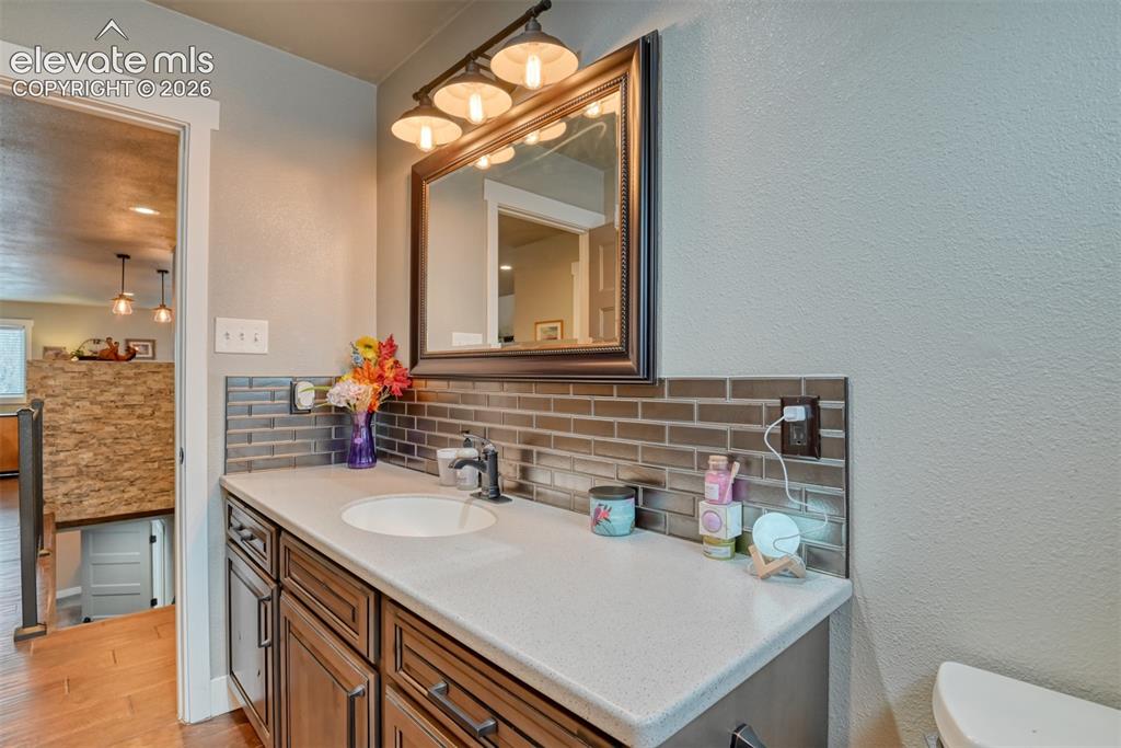 Image 26 of 50: Bathroom featuring tasteful backsplash, vanity, a textured wall, and light