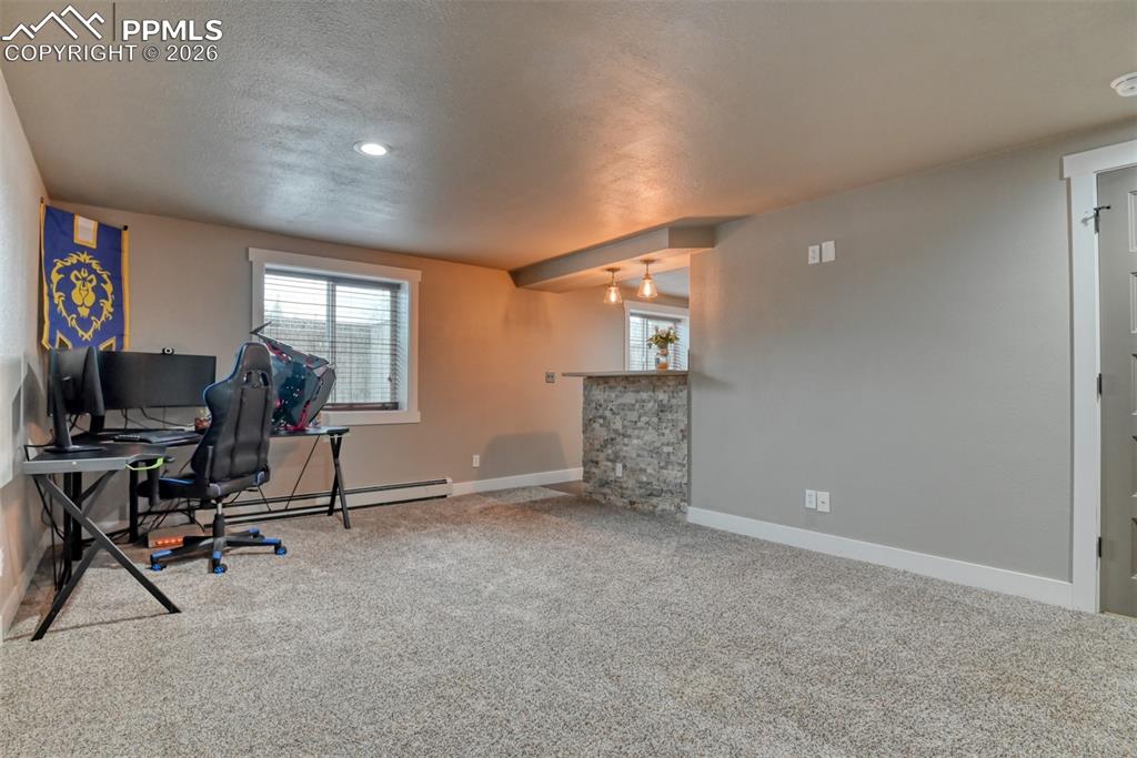 Image 28 of 50: Office space with light carpet and baseboard heating