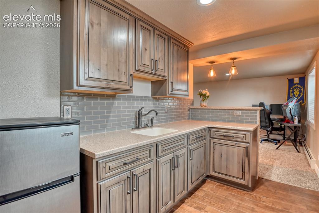 Image 28 of 50: Kitchen featuring stainless steel refrigerator, tasteful backsplash, light