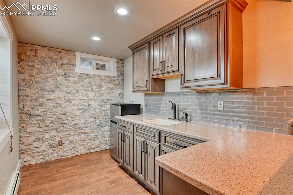 Image 31 of 50: Kitchen with light stone counters, light wood-type flooring, a baseboard ra
