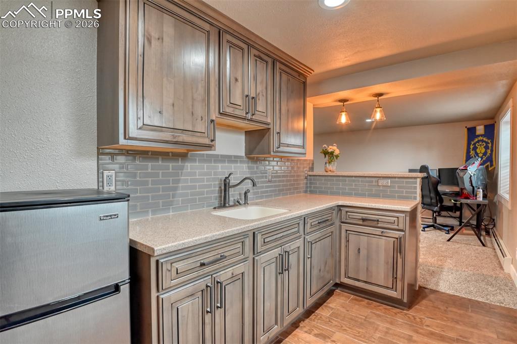 Image 32 of 50: Kitchen featuring stainless steel refrigerator, tasteful backsplash, light