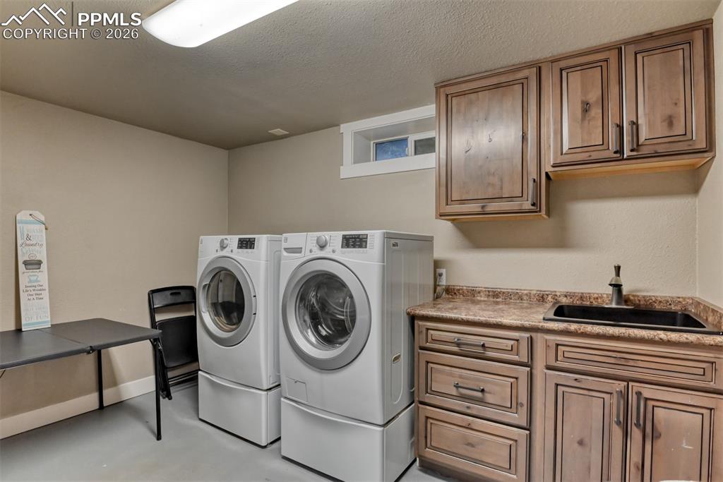 Image 33 of 50: Laundry area featuring a textured ceiling, separate washer and dryer, concr