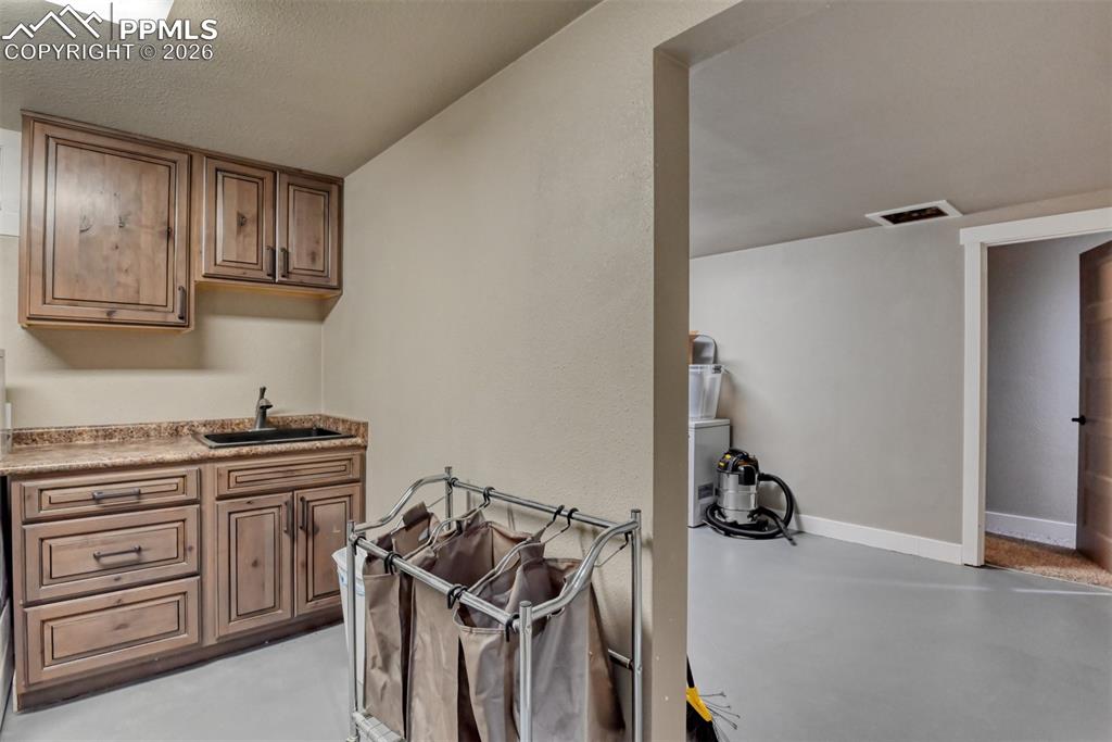 Image 34 of 50: Bar featuring concrete flooring, a textured ceiling, and wood finish cabine
