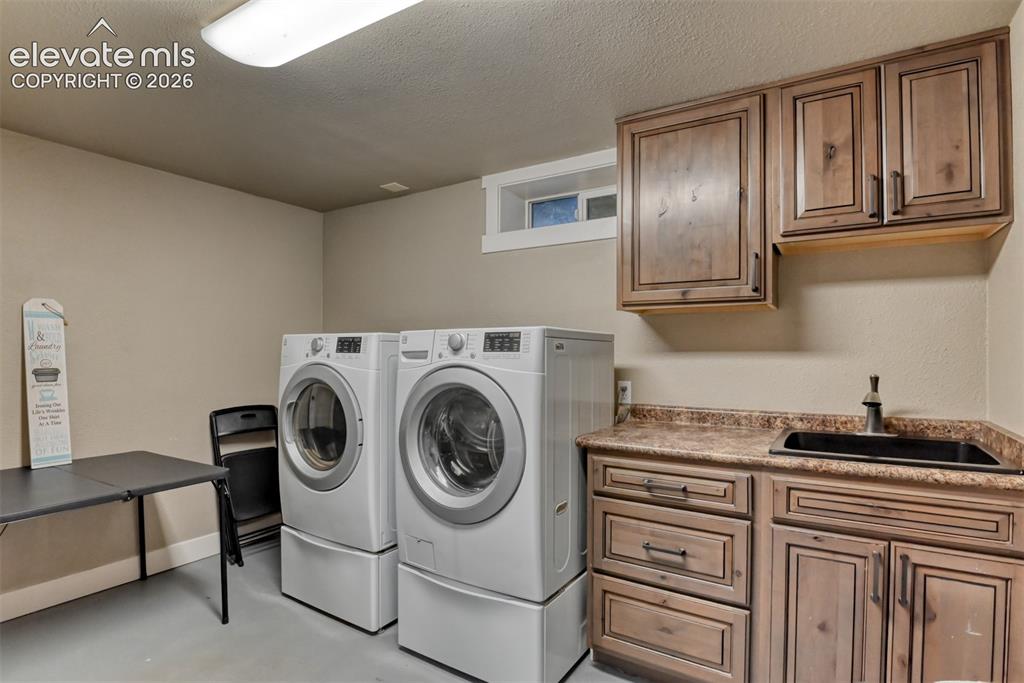 Image 34 of 50: Laundry area featuring a textured ceiling, separate washer and dryer, concr