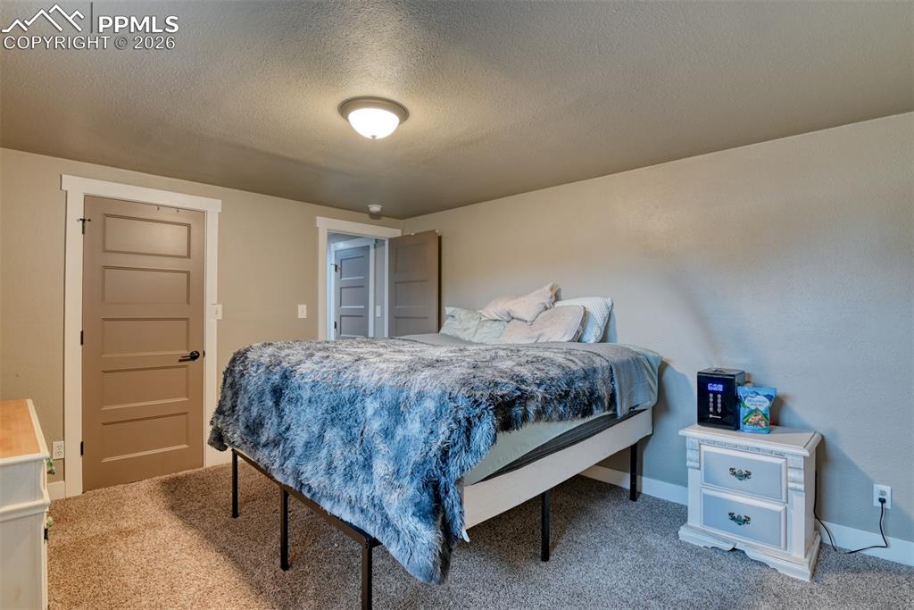 Image 37 of 50: Carpeted bedroom featuring a textured ceiling and baseboards
