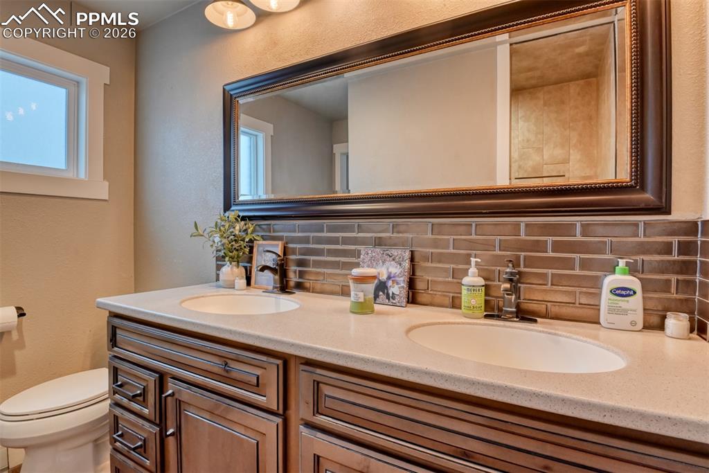 Image 40 of 50: Full bath featuring backsplash, a textured wall, and double vanity