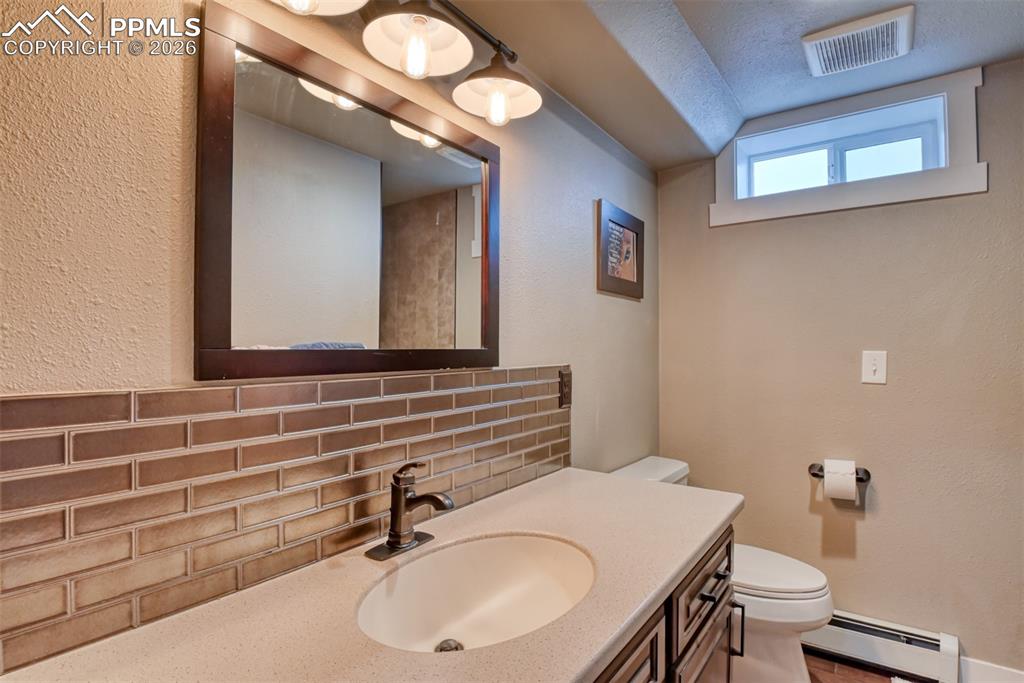 Image 42 of 50: Bathroom featuring vanity, a baseboard heating unit, a textured wall, taste