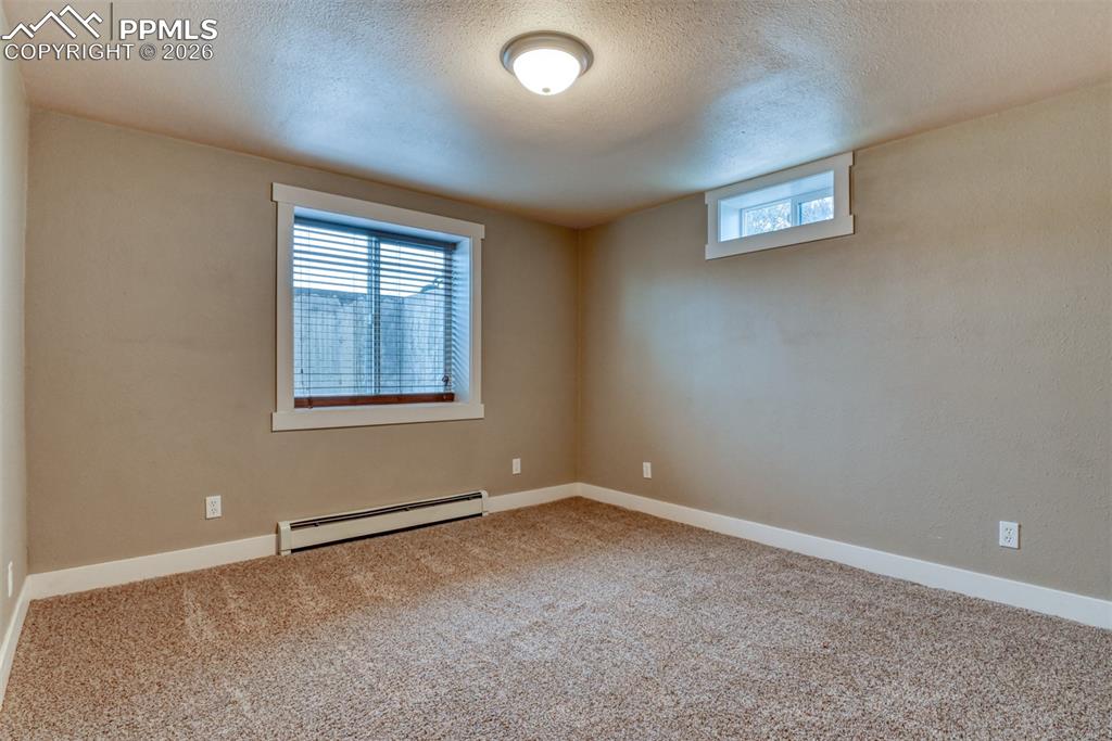 Image 44 of 50: Unfurnished room with a baseboard radiator, light carpet, and a textured ce