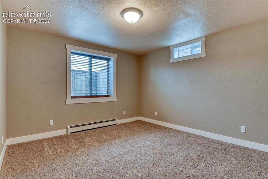 Image 45 of 50: Unfurnished room with a baseboard radiator, light carpet, and a textured ce