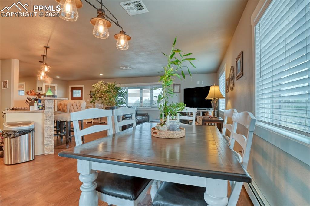 Image 8 of 50: Dining area featuring wood finished floors and baseboard heating