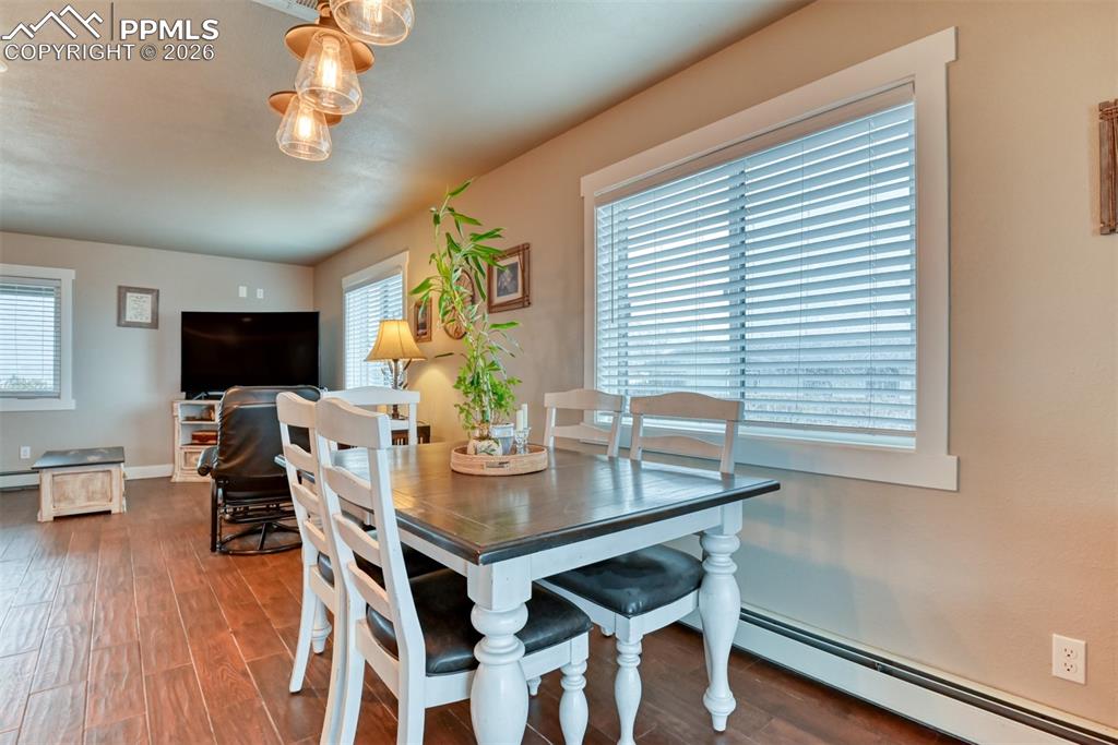 Image 9 of 50: Dining area with a baseboard heating unit and dark wood-style floors