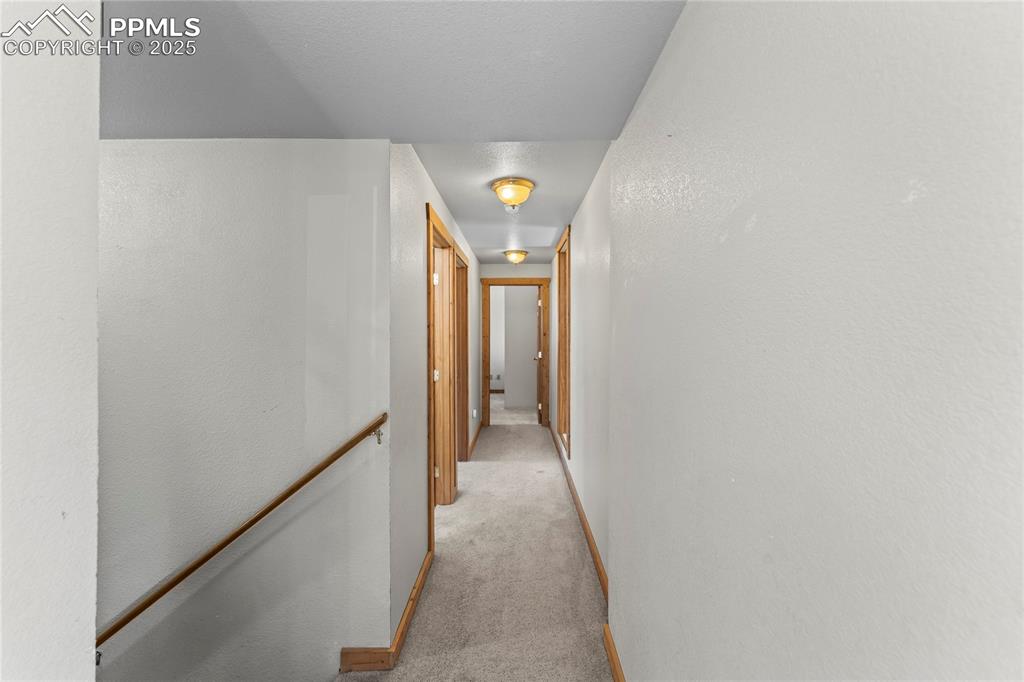 Image 12 of 39: Hallway with light colored carpet and an upstairs landing