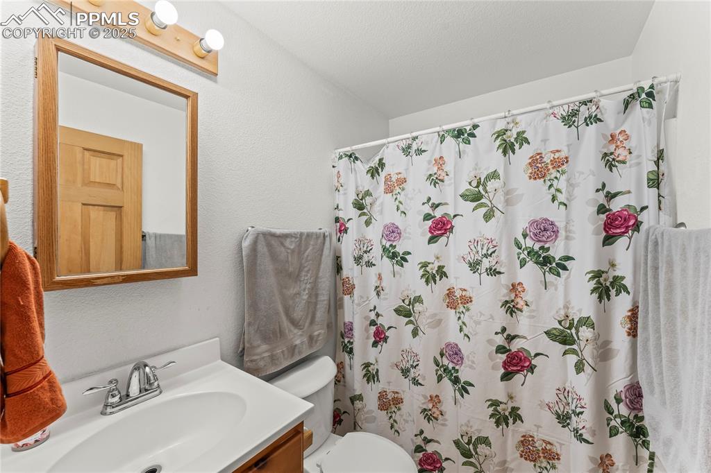 Image 13 of 39: Full bath featuring vanity, a textured wall, and a shower with shower curta