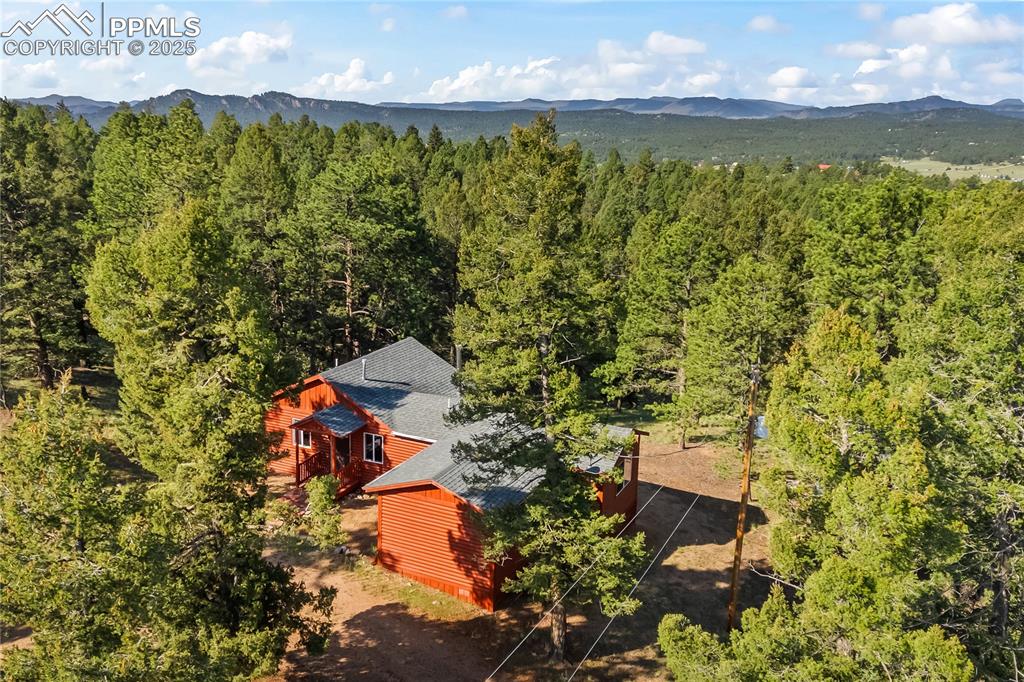 Image 33 of 39: View of subject property featuring a mountainous background and a heavily w