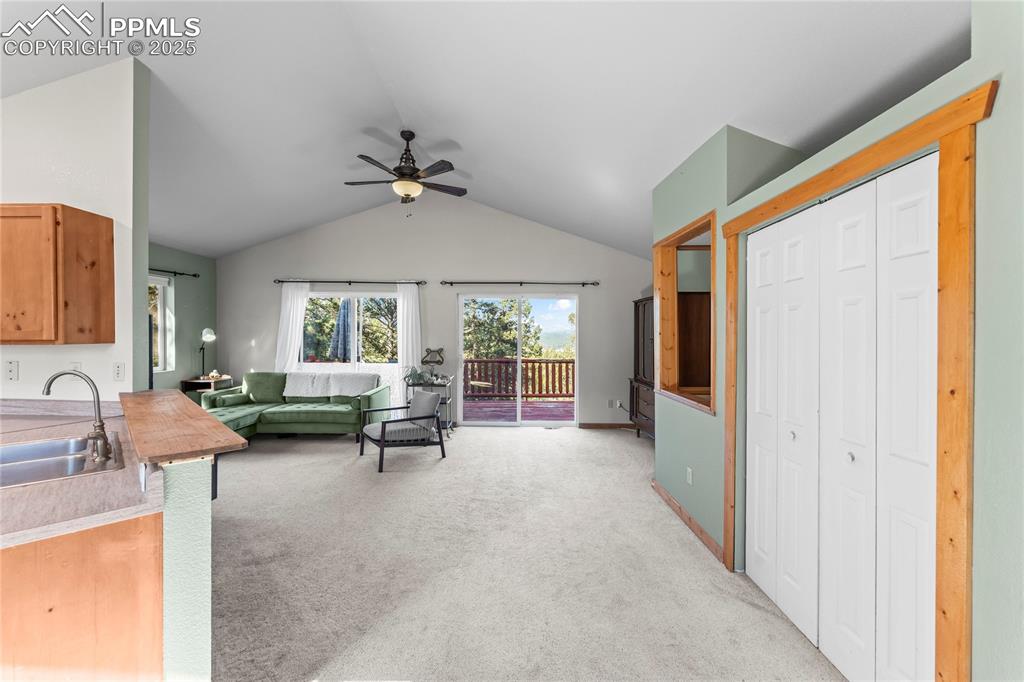 Image 4 of 39: Front entry into living area with light colored carpet, a ceiling fan, and