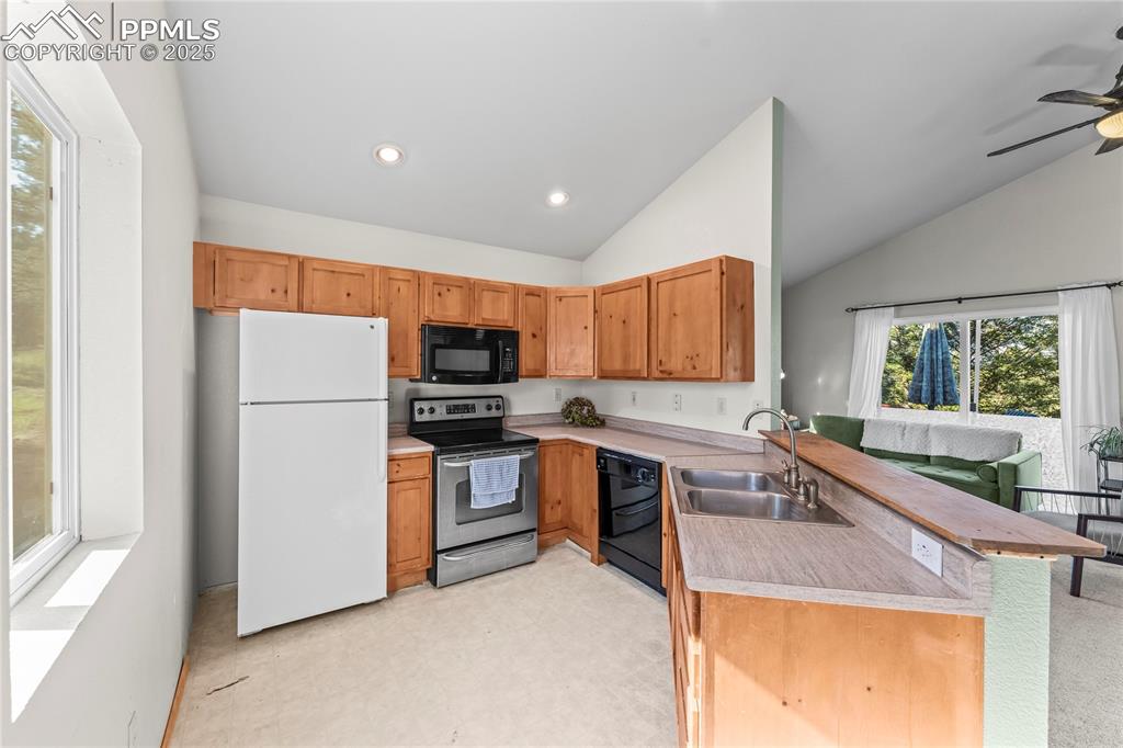 Image 6 of 39: Kitchen featuring a peninsula, black appliances, light countertops, light f