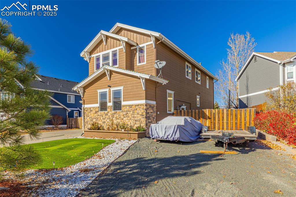Image 3 of 45: Rear view of house with board and batten siding and stone siding