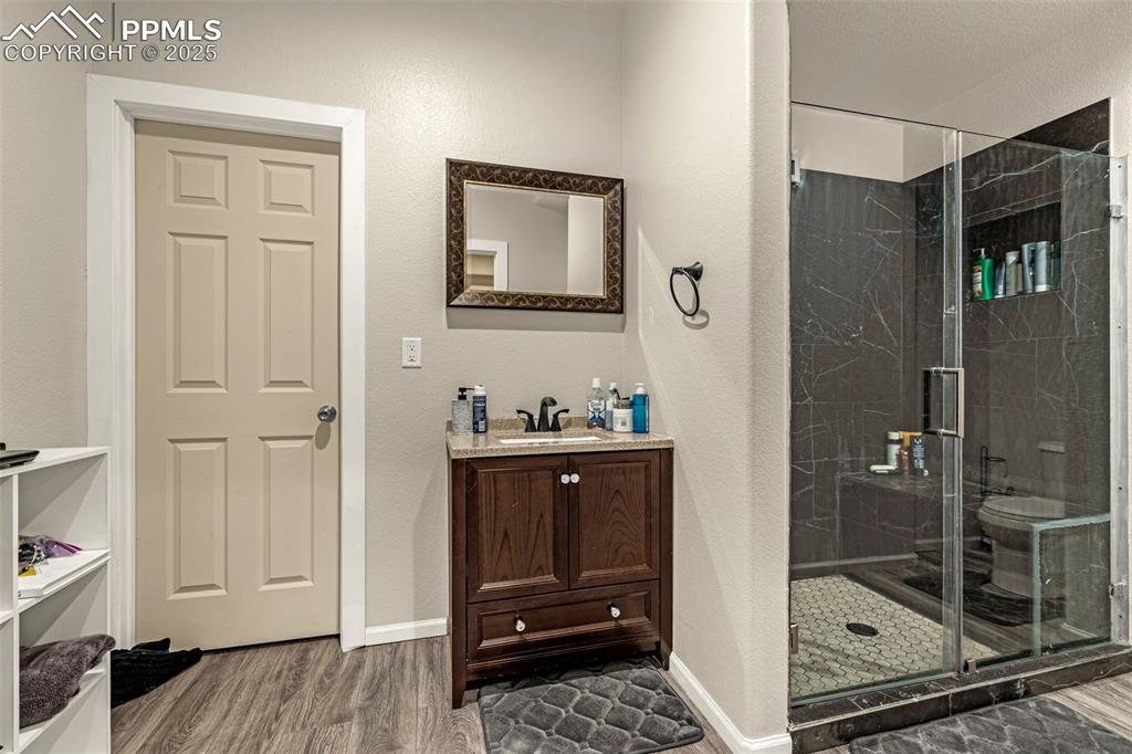 Image 35 of 45: Bathroom with vanity, a marble finish shower, dark wood-style flooring, and