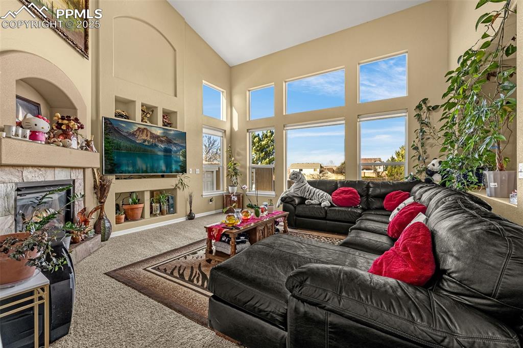 Image 8 of 45: Carpeted living room with a high ceiling and a tile fireplace