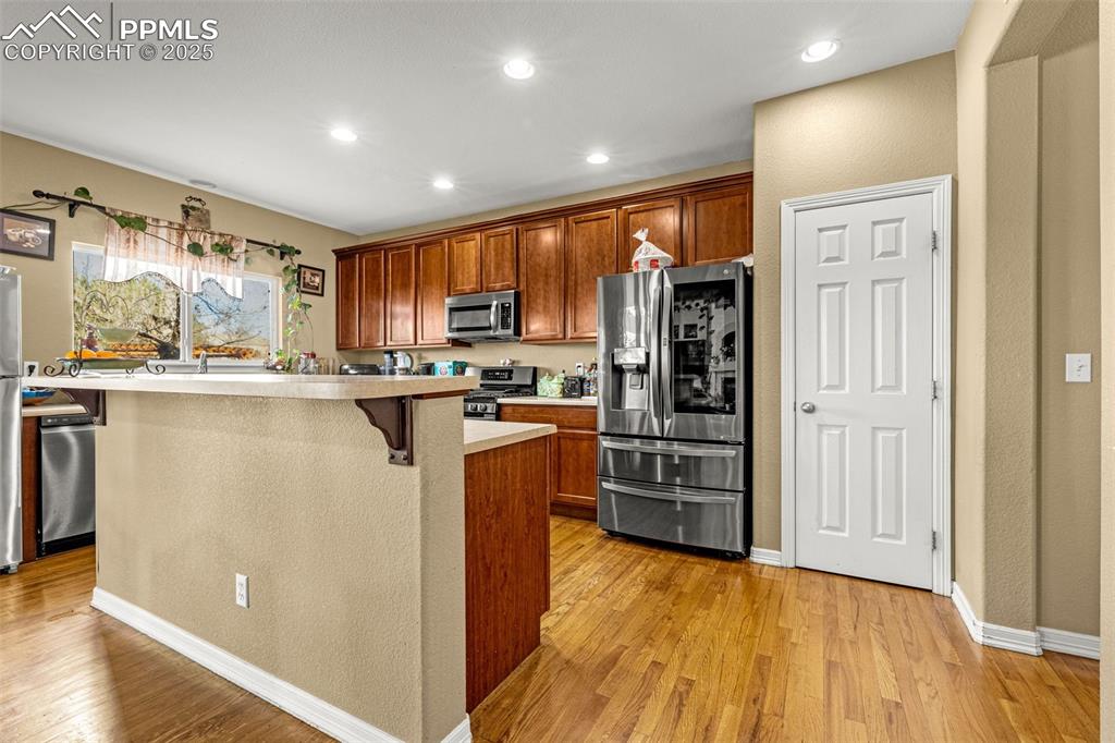 Image 9 of 45: Kitchen featuring light countertops, stainless steel appliances, brown cabi