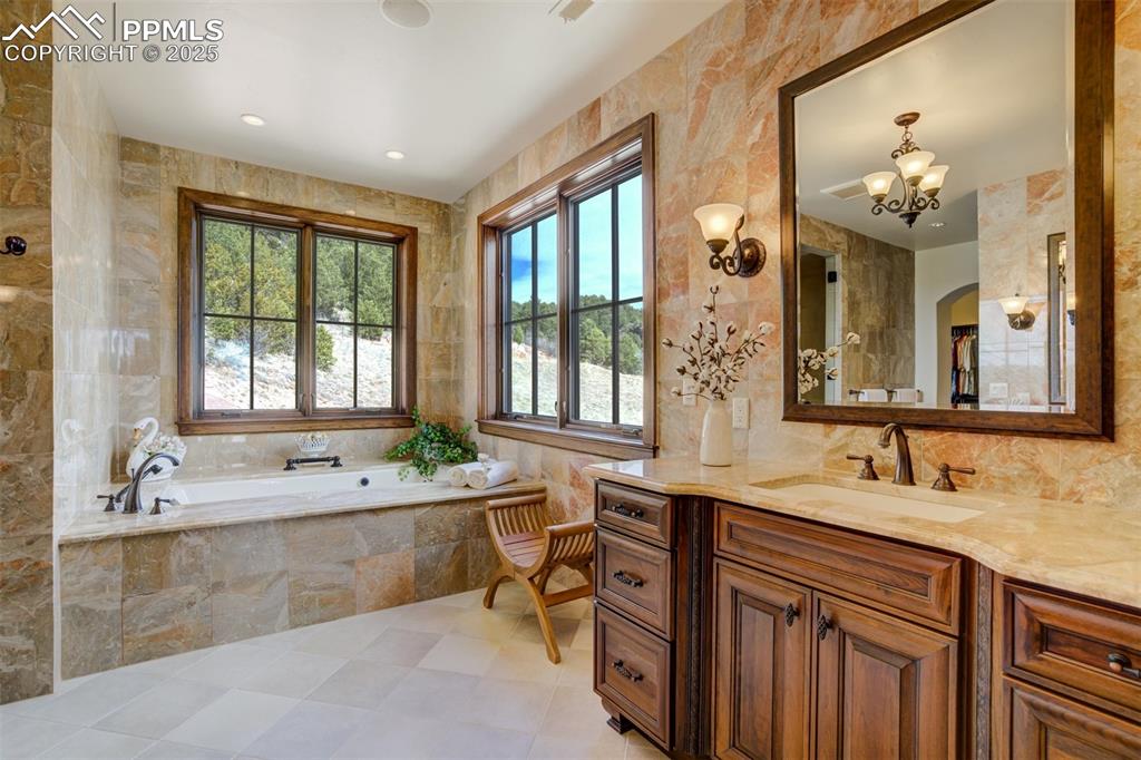 Image 36 of 50: Primary bathroom with soaking tub, 2 separate sinks & floor to ceiling marb