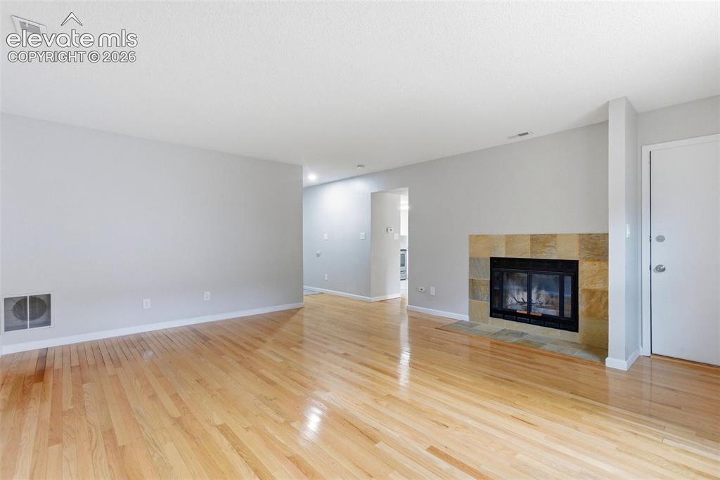 Image 10 of 50: Living area featuring wood-finish flooring, light gray wall paint, and a fi
