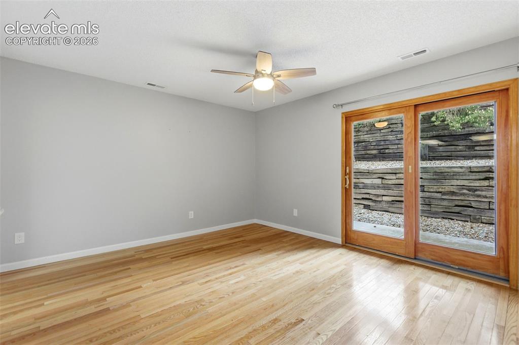 Image 11 of 50: Bright room featuring wood-finish flooring, a ceiling fan with integrated l