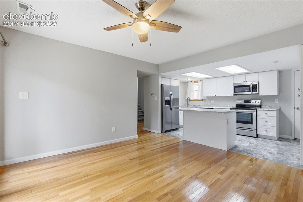 Image 14 of 50: Open-concept living space featuring wood-finish flooring, a ceiling fan wit