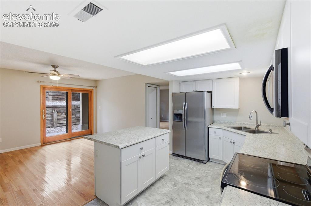 Image 17 of 50: Kitchen featuring white cabinetry, light-toned countertops, stainless steel