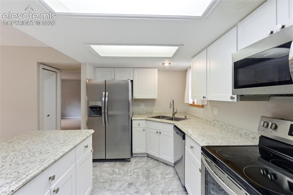 Image 18 of 50: Kitchen featuring white cabinetry, light-toned countertops, recessed lighti